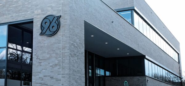 Modernes Gebäude mit einem markanten 96-Logo auf einer hellen Ziegelwand.