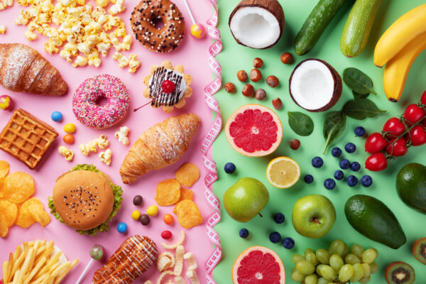 Ein geteiltes Bild von Junk Food auf rosa und frischem Obst und Gemüse auf grünem Hintergrund.